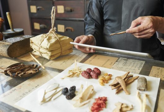 Chinese medicine practitioner selecting ingredients Traditional Chinese medicine practitioner with tablet computer selecting dy herbs, mushroom and roots for recipe